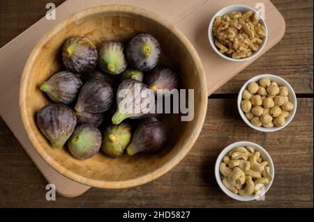 Vue de dessus de figues, noix, noix de cajou et noisettes dans un bol en bois sur une table en bois, verticale, avec espace de copie.Photo de haute qualité Banque D'Images