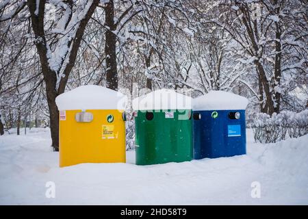 De grandes poubelles de collecte de déchets sont placées dans une rue publique sous la neige. Banque D'Images