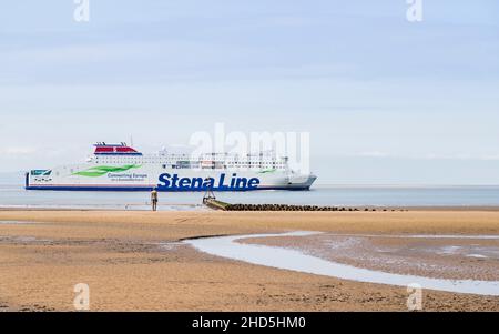 Le ferry Stena Embla quitte la rivière Mersey en passant par un Iron Man sur la plage de Crosby. Banque D'Images