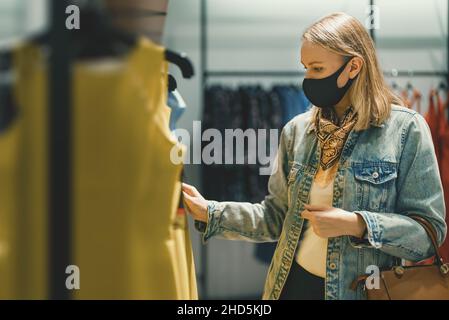 La femme en masque médical choisit la robe. Banque D'Images