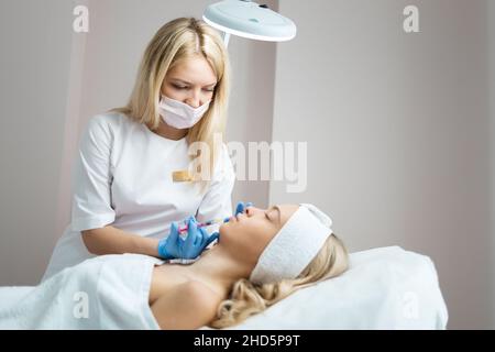 Femme médecin cosmetologiste fait des injections d'acide hyaluronique pour l'augmentation des lèvres du patient Banque D'Images