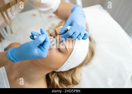 Le cosmétologue fait des injections antirides rajeunissants sur le visage d'une belle femme.Injection de beauté du front Banque D'Images