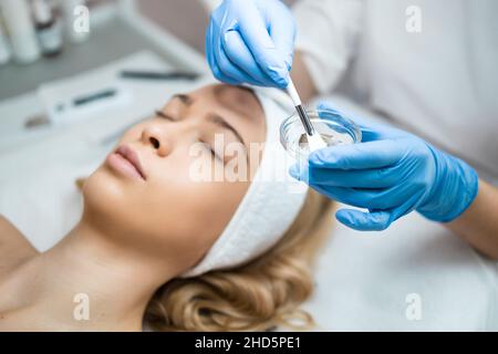 Médecin cosmetologiste applique un masque hydratant transparent au visage d'une femme.Préparation de la peau du visage pour la procédure de décollement par ultrasons Banque D'Images