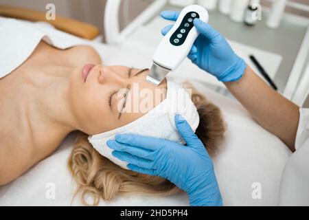 Médecin de beauté avec scabre ultrasonique faisant la procédure de nettoyage ultrasonique du visage.Cosmétologie et soin du visage Banque D'Images