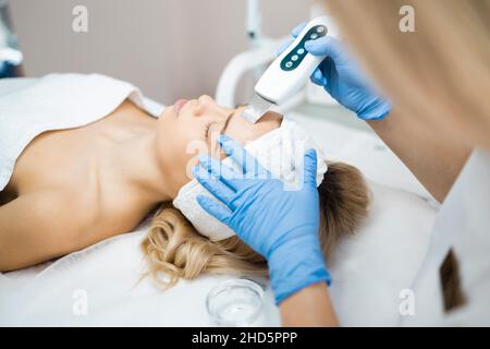 Belle femme qui obtient le nettoyage de peau à ultrasons au salon de beauté.Gommage facial par cavitation ultrasonique Banque D'Images