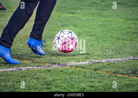 Joueur de football amateur courant avec le ballon sur l'herbe verte artificielle du terrain de football.Compétition, école de football, tournoi.Sport d'action Banque D'Images