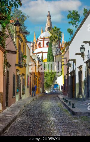 L'étroite rue Cobblestone Aldama offre une vue sur le Parroquia San Miguel de Allende Archangel Church Dome à côté des maisons et des trottoirs à San Miguel Banque D'Images