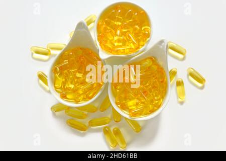 Huile de poisson.omega 3 capsules de gélatine dans des tasses en céramique blanche sur fond blanc.acides gras oméga.Suppléments naturels Banque D'Images