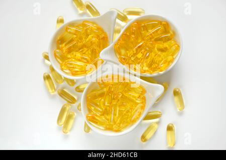 Huile de poisson.omega 3 capsules de gélatine dans des tasses en céramique blanche sur fond blanc.acides gras oméga.Suppléments naturels et vitamine Banque D'Images