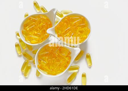 capsules de gélatine omega 3 en tasses blanches sur fond blanc.acides gras oméga.Suppléments naturels et vitamine.huile de poisson. Banque D'Images