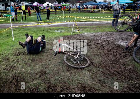 WA20605-00......WASHINGTON - un cycliste se renverse sur un coin boueux lors d'une course de cyclocross féminin. Banque D'Images