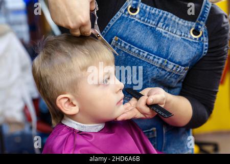 Un garçon dans un salon de coiffure pour enfants.Coupe de cheveux d'un enfant dans un coiffeur moderne pour enfants. Banque D'Images