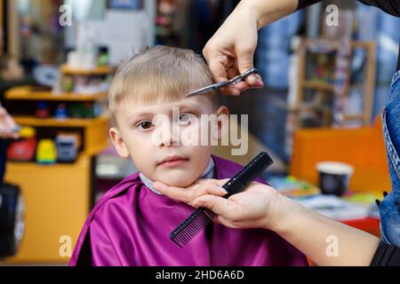 Un garçon dans un salon de coiffure pour enfants.Coupe de cheveux d'un enfant dans un coiffeur moderne pour enfants. Banque D'Images