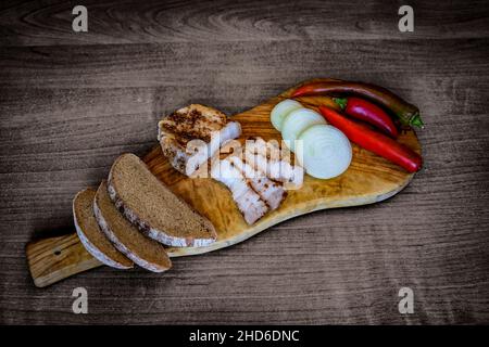 Image vintage - pain en tranches, bacon épicé, oignon et piment sur une planche à découper en bois. Banque D'Images