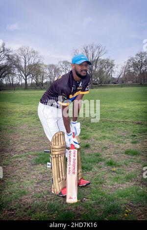 Un batteur de cricket américaine dans la vingtaine qui pose pour une photo lors d'un tournoi en Baisley Pond Park en Jamaïque, Queens, New York. Banque D'Images