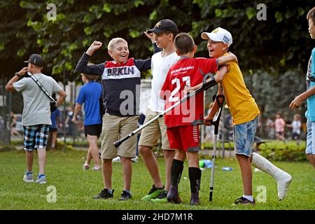 Un joueur de football pour enfant fête avec un coéquipier avec une jambe en plâtre après une blessure au football Banque D'Images