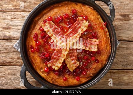 Une crêpe suédoise aux œufs avec du bacon croustillant et des canneberges se trouve dans une poêle sur la table. Vue horizontale du dessus Banque D'Images