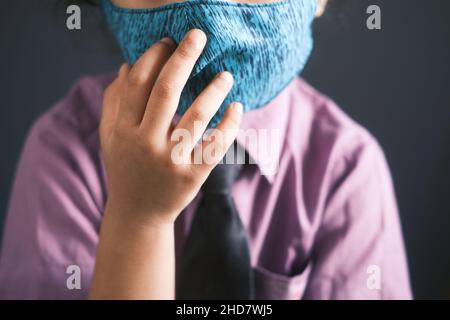 une fille heureuse en vert d'école portant un masque Banque D'Images
