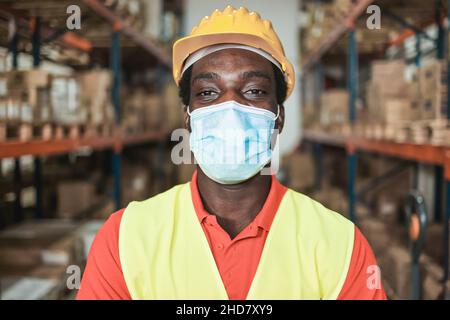 Portrait de l'homme ouvrier africain à l'intérieur de l'entrepôt tout en portant un masque de protection - Focus sur le visage Banque D'Images