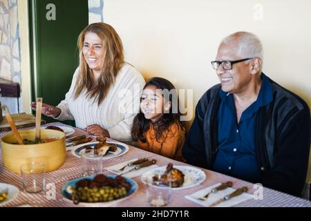 Heureux grands-parents latins ayant plaisir à manger avec sa petite-fille à la maison - Focus sur le visage de grand-mère Banque D'Images