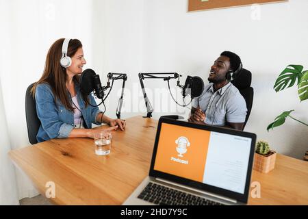 Hôtes ayant une session de podcast ensemble - intervenants multiraciaux faisant un entretien pendant la diffusion en direct - Focus sur le visage féminin Banque D'Images