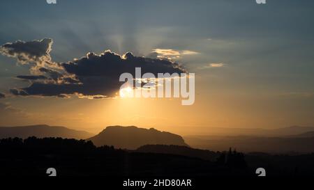 Une lumière et des rayons du soleil magnifiques tandis que le soleil se couche de derrière un nuage juste avant le coucher du soleil sur les collines et les vallées de l'espagne valenciana Banque D'Images