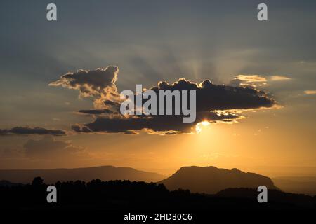 Une lumière et des rayons du soleil magnifiques tandis que le soleil se couche de derrière un nuage juste avant le coucher du soleil sur les collines de l'espagne valenciana Banque D'Images