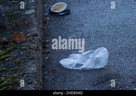 Sac en plastique et tasse à café en papier couchés dans la rue avec attention sur le sac en plastique Banque D'Images