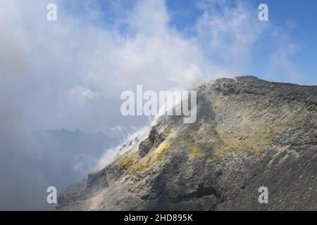 Sommet du cratère du volcan Etna en Sicile, Italie.Dépôts de soufre jaune (soufre) sur les roches grises et brunes.Ciel bleu avec nuages blancs. Banque D'Images