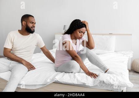 Grave jeune homme noir calme à triste femme désespéré déprimée, s'asseoir sur le lit dans la chambre à l'intérieur Banque D'Images