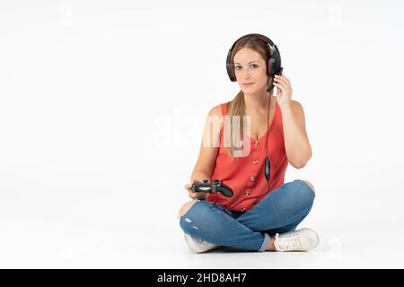 Femme jouant à des jeux vidéo avec une manette et un casque dans un fond blanc Banque D'Images