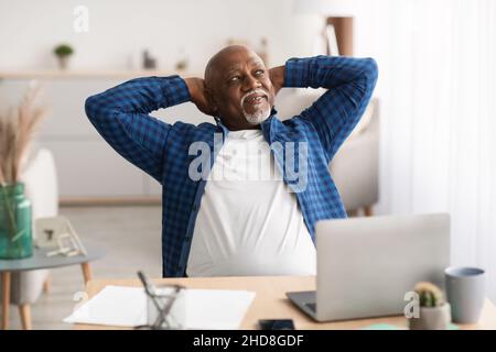 Un homme d'affaires africain détendu se tenant les mains derrière Head in Office Banque D'Images