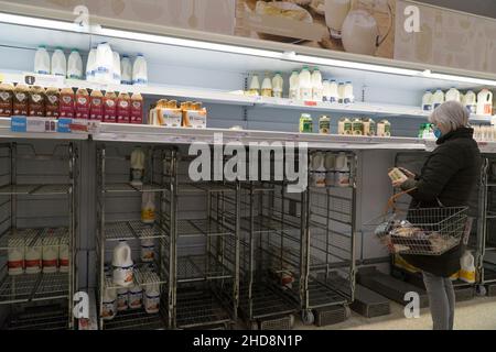 Londres, Royaume-Uni, 4 janvier 2022 : le lendemain des vacances du nouvel an, une femme envisage ses options limitées d'achat de lait dans cette succursale de Sainsbury's à Clapham.Ils n'avaient qu'un très petit approvisionnement en lait à l'heure du déjeuner, et aucun des types de marques propres les plus abordables.Anna Watson/Alay Live News Banque D'Images