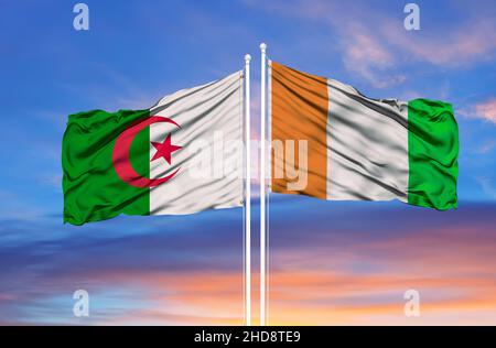 Algérie et Côte d'Ivoire deux drapeaux sur les mâts et ciel bleu nuageux Banque D'Images