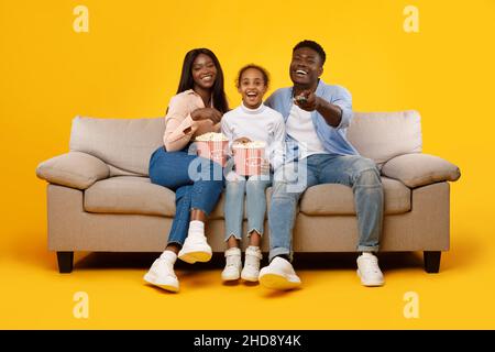 Bonne famille regardant la télévision avec pop-corn sur le canapé Banque D'Images