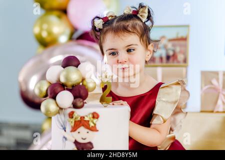 Portrait d'une jolie petite fille souriante debout à côté du gâteau d'anniversaire et de la bougie.Adorable bébé fille anniversaire photoshoot Banque D'Images