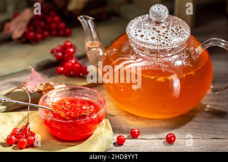 Confiture de viburnum dans un bol en verre sur la table en bois de style rustique avec une boisson chaude d'hiver et des baies de viburnum Banque D'Images
