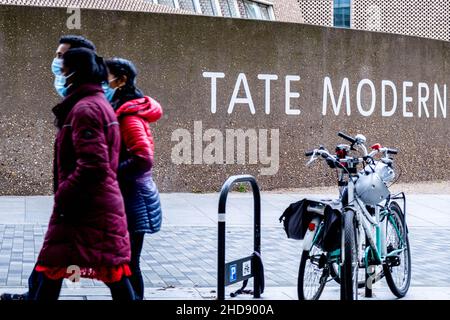 Londres Angleterre Royaume-Uni janvier 02 2022, petit groupe de familles de personnes portant des masques protecteurs de visage marchant devant Un signe moderne de Tate Banque D'Images