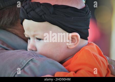 Un enfant de l'année avec un bandeau noir et une chemise orange Halloween avec son père qui achète des citrouilles Banque D'Images