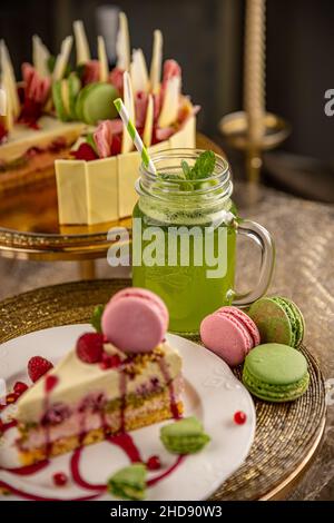 Délicieux gâteau d'anniversaire décoré de macarons et servi avec de la limonade à la menthe Banque D'Images