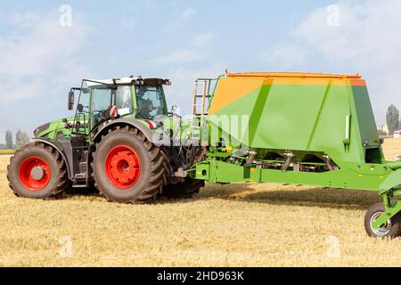 Le semoir en tant qu'unité remorquée sur un tracteur assure une excellente préparation du sol avant de semer sur le fond d'un champ agricole récolté. Banque D'Images