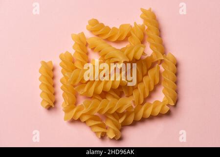 une poignée de pâtes fusilli se visse sur fond rose Banque D'Images