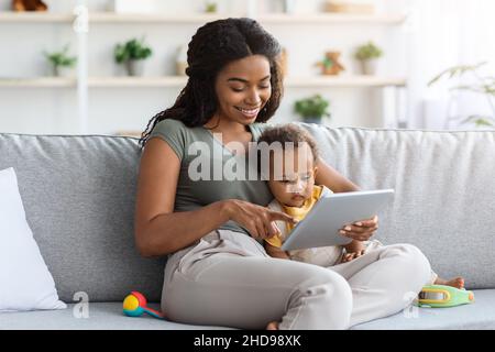 Bébés et gadgets.Happy Black Woman et Toddler son utilisant la tablette numérique Banque D'Images