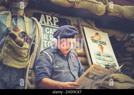 Gros plan de la guerre, 1940 ARP warden (air raid précaution) lisant le journal d'époque, Severn Valley Heritage Railway 1940s WW2 événement d'été Royaume-Uni. Banque D'Images