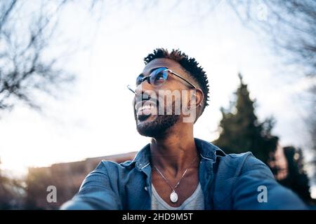 Beau latino homme avec des lunettes prenant un selfie avec son smartphone dans la rue Banque D'Images