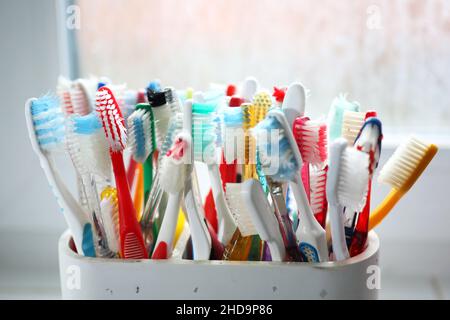 Une sélection de brosses à dents en plastique colorées dans un pot dans une salle de bains à Chichester, West Sussex, Royaume-Uni. Banque D'Images