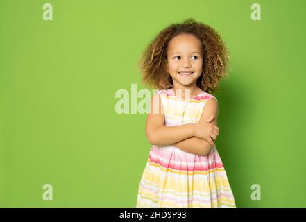 Photo de charmante petite fille excitée avec ses mains pliées debout sur fond vert. Banque D'Images