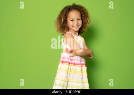 Photo de charmante petite fille excitée avec ses mains pliées debout sur fond vert. Banque D'Images