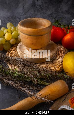 Encore la vie, les raisins et les tomates dans la composition abstraite et intense couleur.Scène avec mortier pour écraser la nourriture dans le ton de bois antique. Banque D'Images
