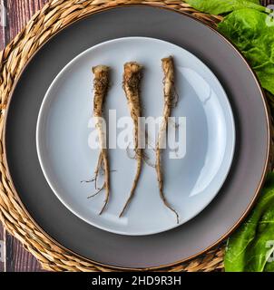 Vue de dessus des racines de chicorée sur une assiette blanche avec de la laitue fraîche sur le côté Banque D'Images